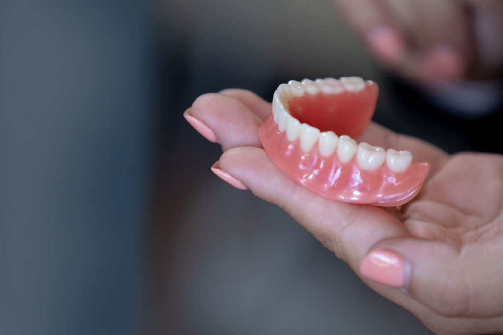woman holding denture Select Dental